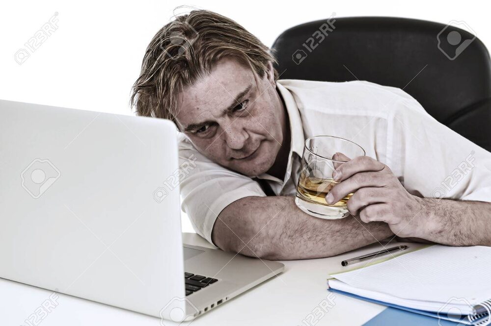 74385847-gaspillé-et-désordre-homme-d-affaires-alcoolique-boire-whisky-travaillant-au-bureau-d-ordinateur-por.jpg